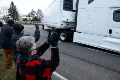 People cheer as trucks carry the first shipment of the Covid-19 vaccine to leave Pfizer's facility in Michigan . ©AFP JEFF KOWALSKY