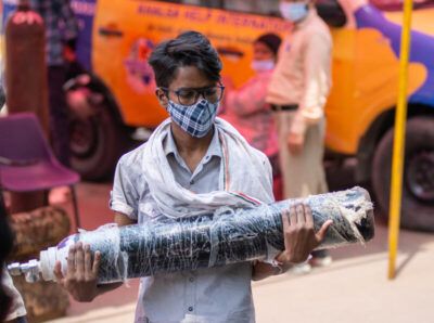 Young boy in India holds an oxygen tank during the most devastating spread of COVID-19