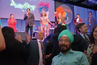 TiE Content Chair Rajiv Patel (c) and TiE Inflect Convener R. Paul Singh (r) at TiE Banquet dance at mesmerizing music by Sudesh Bhosle (center on stage). page-tie-06-dsc_8060